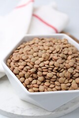 Raw brown lentils on white table, closeup