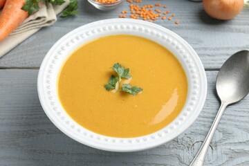 Delicious lentil cream soup served on grey wooden table, closeup