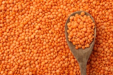 Raw red lentils and spoon as background, closeup view