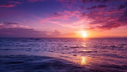 Obraz premium serene sunset over calm ocean awash in vibrant purple and pink hues reflecting light on water surface ideal for tranquil nature imagery or backgrounds