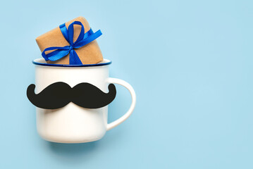 Happy Father's Day. Top view of cup of coffee with false mustache and gift box with copy space for...
