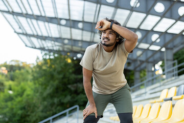 Tired athlete resting after active physical exercise and running, man breathing and relaxing.