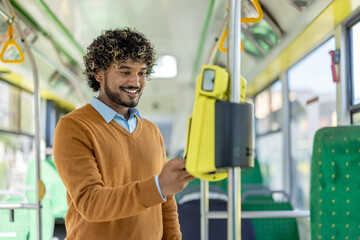 Young man buys tickets for public transport inside, using an app on his phone and contactless...