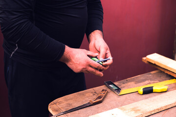 Carpenter with ruler measuring wood plank.