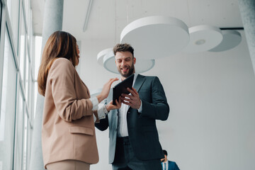 Business colleagues using tablet and discussing work in modern office