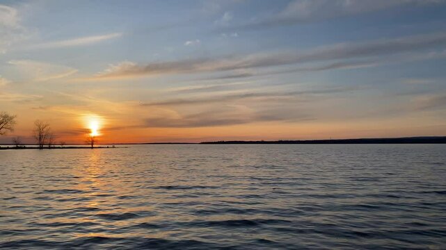 Sunset Over Lake with Silhouetted Trees and Reflected Sky, The sky reflects in the water while soft clouds