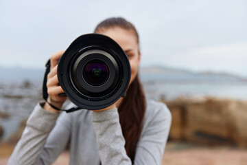 Young woman capturing stunning nature photography with camera, showcasing creativity and passion for photography against a scenic backdrop