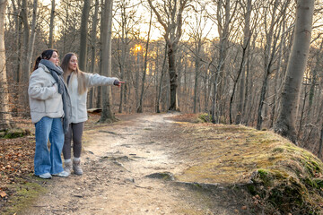 Fototapeta premium Two women in the forest. Woman pointing at the scenery. People in nature.