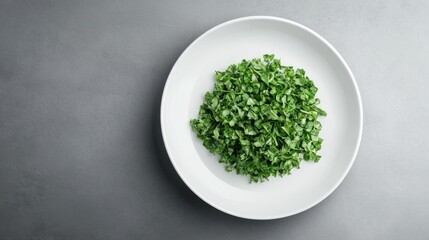 Chopped green herbs on a white plate against a gray background.