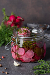 Marinated sliced radish with dill and garlic in open glass jar