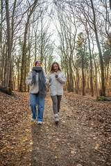 Obraz premium Two female friends on a walk in the forest. Friends walking through the forest. People in nature.