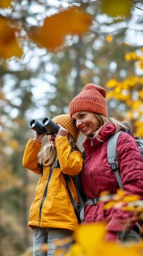 mother and daughter exploring autumn forest with binoculars, discovering adventure in nature