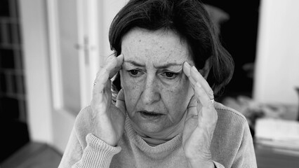 Elderly woman with severe headache, hands pressing against temples, deep concentration and mental...