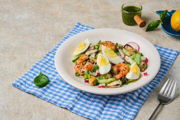 Salad of fresh cucumber, radish and eggs with seafood in a ceramic plate on a light concrete background. Salad recipes.