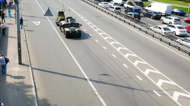 Public transport moving on the right side of a city road ,while military vehicles move on the left side.