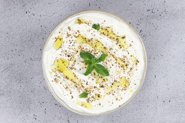 Labneh - creamy yoghurt cheese with olive oil and zaatar on gray background. Top view. Middle East cuisine