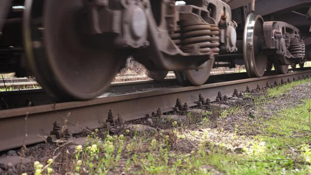 Close-up of freight train rolling stock. Low-angle close-up of steel freight car wheels rattling on concrete sleepers. Loaded hopper cars moving. High quality 4k footage