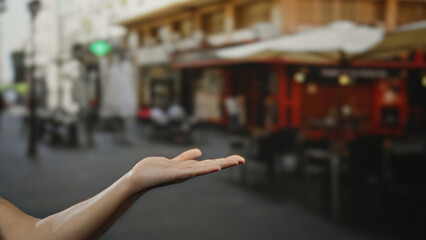 Man's hand extended invitingly in urban coffee shop terrace, capturing the vibrancy of city street...