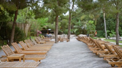 Luxury tropical resort with defocused view of wooden lounge chairs on a sunny terrace surrounded by...