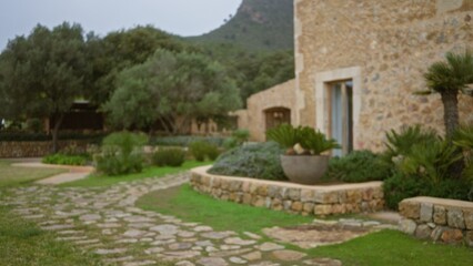 Blurred view of a rustic stone house with a winding path, lush greenery, and a mountainous...