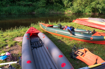 Kayaks on the river bank. Inflatable kayaks near a body of water. Water sports, rafting on kayaks.