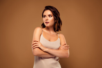 Obraz premium Portrait of a beautiful young woman posing confidently against a beige background, showing elegance