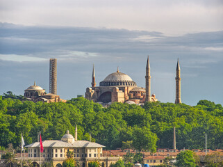 Naklejka premium Iconic Hagia Sophia mosque with its domes and minarets rising above green trees in Istanbul, Turkey