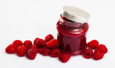 Jar of sweet raspberry jam and fresh ripe berries on white surface