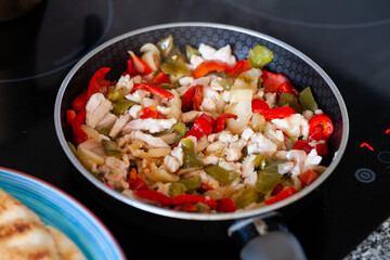 Chopped chicken breast with onion and peppers on frying pan, preparation of filling for pita
