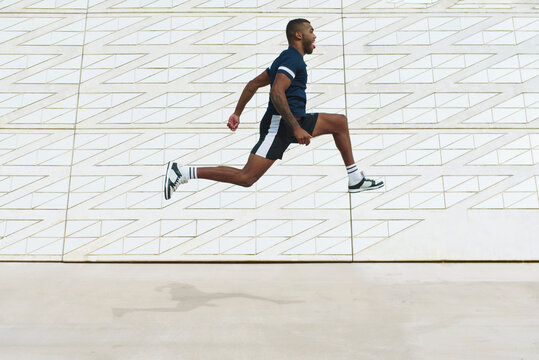 Athletic black man captured mid-air against urban wall