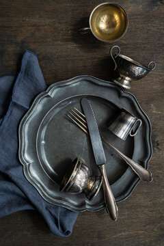 Vintage metal tableware with cutlery and dark napkin