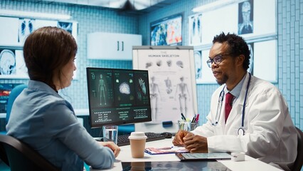Doctor reading x ray imaging for a diagnostic report at consultation, discussing with a patient...