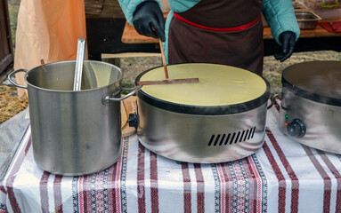 Vendor using heated griddles to prepare crepe batter at a festive outdoor market setting, showcasing traditional culinary techniques and attracting food enthusiasts