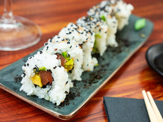 Uramaki. California salmon roll on wooden background. Salmon, avocado, rice, sesame. Japanese menu concept.