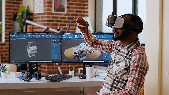 African american software developer working with virtual reality headset and artificial intelligence to create new industrial prototypes and manufacturing tools on CAD software. Camera B.