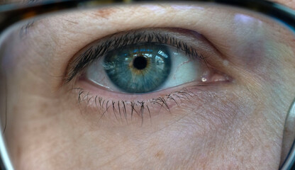 Close up of a hazel eye behind glasses.
