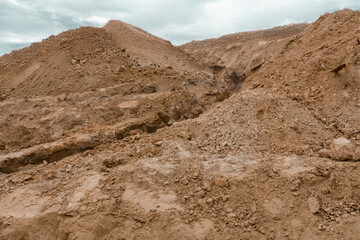 Close-up view of a clay and sand quarry, showcasing layers of earth in warm shades of brown and yellow. The rough, textured surface captures the raw beauty of natural materials