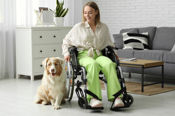Young woman in wheelchair with service dog at home
