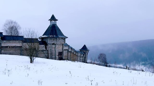 A log fortress wall covered with snow after a blizzard. Scenery for the film "The Heart of Parma" among snow-covered forests, hills and mountains in Perm Krai, Russia. The crooked cross in the Lip.4K