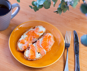 Light and healthy breakfast - sandwiches of bran bread and salmon and cup of hot black tea coffee