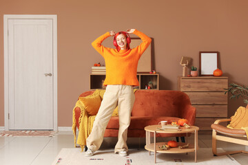 Young happy woman in headphones dancing and listening music at home