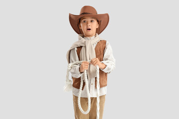 Shocked little cowboy with lasso on light background