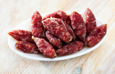 Traditional Catalan dry cured mini sausage secallona on wooden background