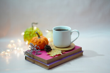 Beautiful autumn still life consisting of books, white cup of tea and bright pumpkins