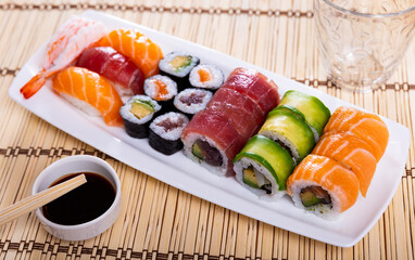 Sushi set - uramaki roll and nigiri is served in white narrow rectangular plate. Traditional Japanese Asian cuisine, gastronomy