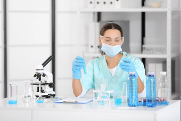 Female young scientist with professional glassware examining water quality in research laboratory