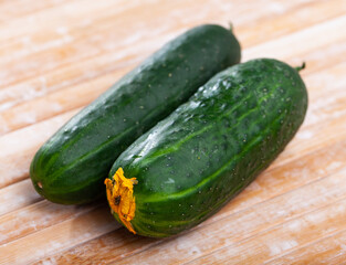 Ripe cucumbers and knife on wooden cutting board