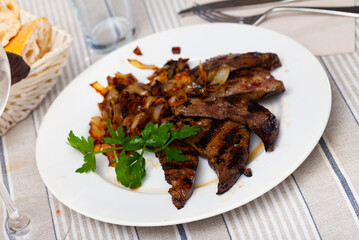 Appetizing sliced pork liver fried with onion garnished with fresh greens