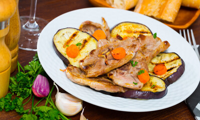 Delicious broiled lamb loin chops served on white plate with grilled eggplant and carrots..
