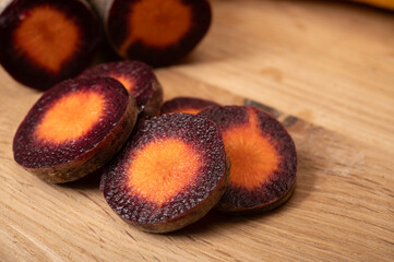 Fototapeta premium Colorful fresh raw purple, yellow, red and purple-orange carrots roots vegetables from greenhouse in the Netherlands